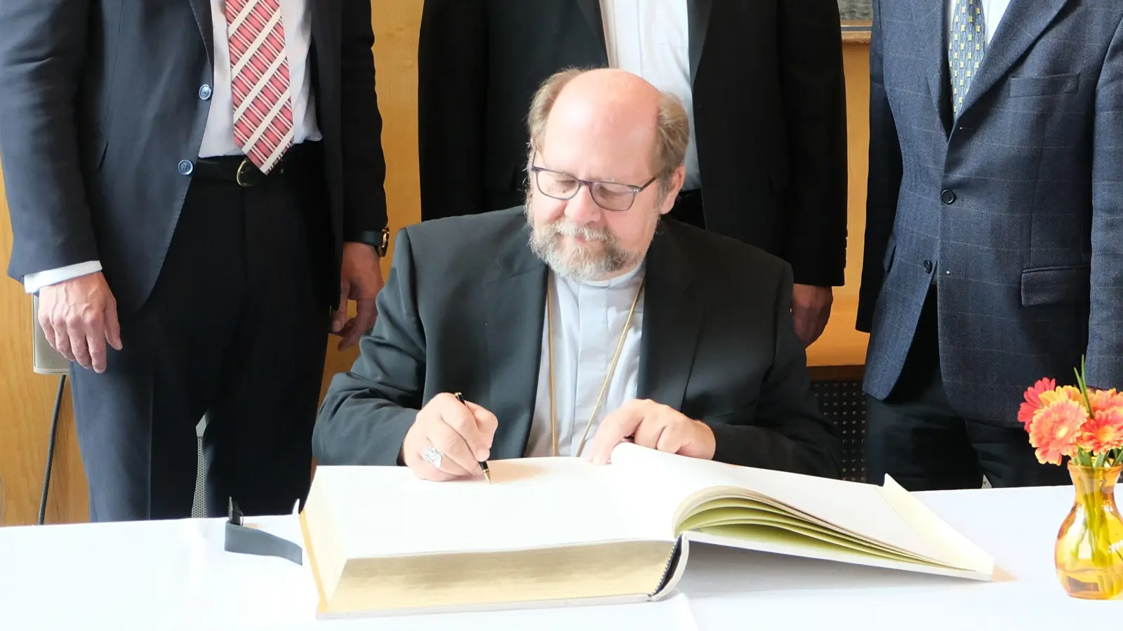 Beim Eintrag ins Goldene Buch (von links): Landrat Martin Bayerstorfer, Landkreisdekan Michael Bayer, stellvertretender Landkreisdekan Josef Kriechbaumer, weiterer stellvertretender Landrat Rainer Mehringer. Sitzend Weihbischof Wolfgang Bischof. (Foto: Landratsamt Erding)