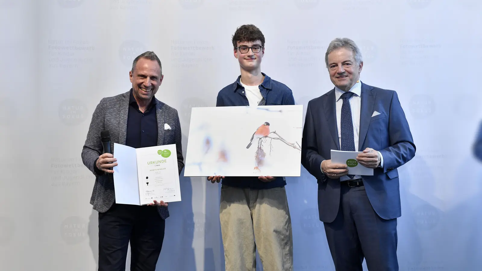 Ein Gimpelmännchen fotografierte Moriz Winkler (Mitte) und kam damit auf Platz 3 in der Kategorie „Magie der Farben” (AK3: 15-18 Jahre). Umweltminister Thorsten Glauber (links) und Michael Apel (Leiter des Museums Mensch und Natur) gratulierten. (Foto: Marcus Schlaf)