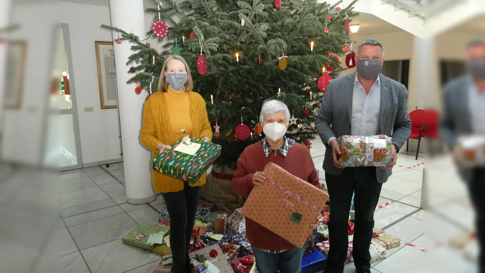 Vor dem Wunschbaum mit den Geschenken (v. li.): Zweite Bürgermeisterin Bianka Poschenrieder, Elisabeth Nuspl und Erster Bürgermeister Piet Mayr. (Foto: Gemeinde Zorneding)