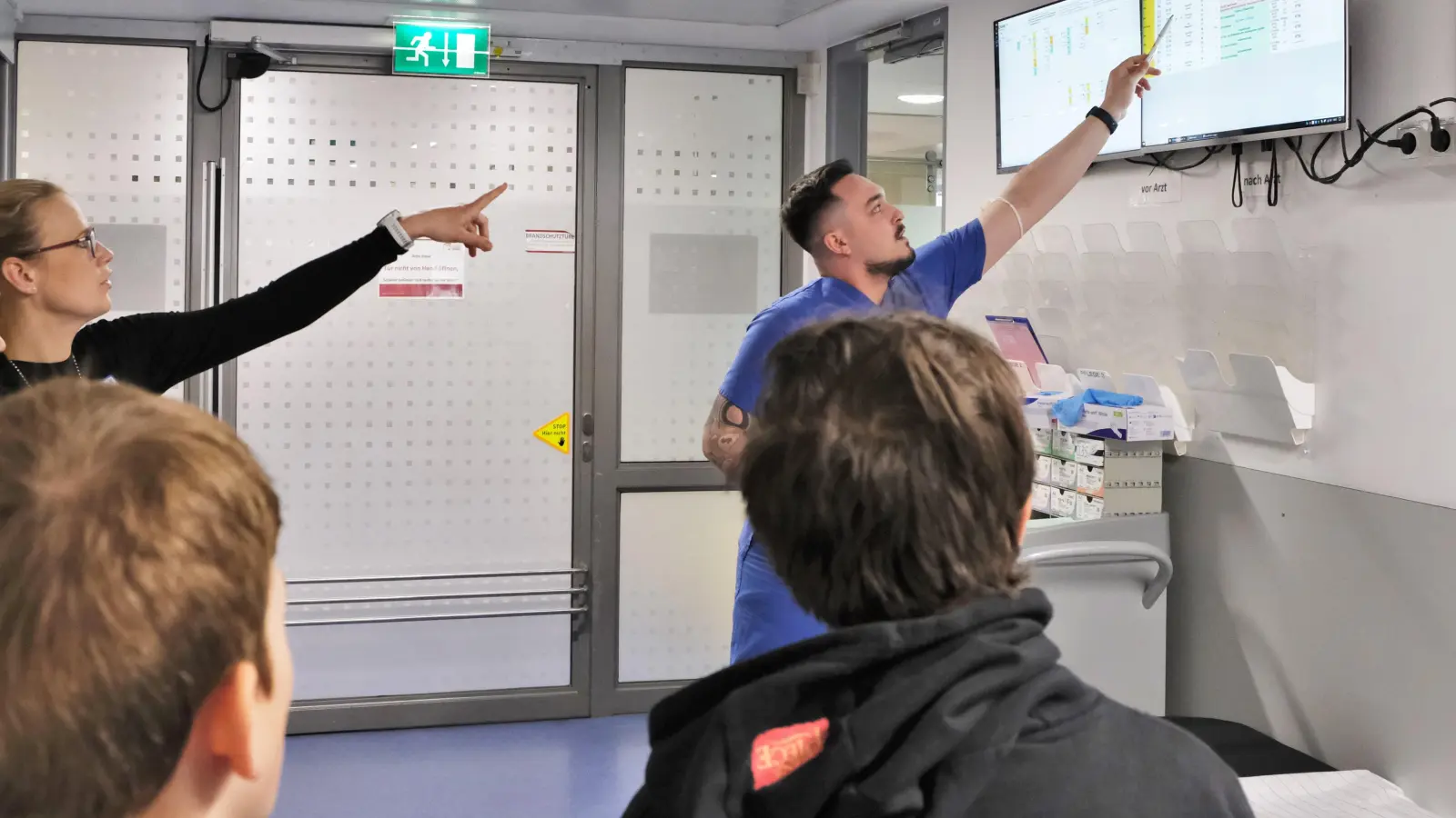 Die Leiterin der zentralen Praxisanleitung, Britta Schichtl, und Pflegefachmann Belmin Dzigum erläutern den Schülern das Triage-System in der Notaufnahme. (Foto: Landratsamt Erding)