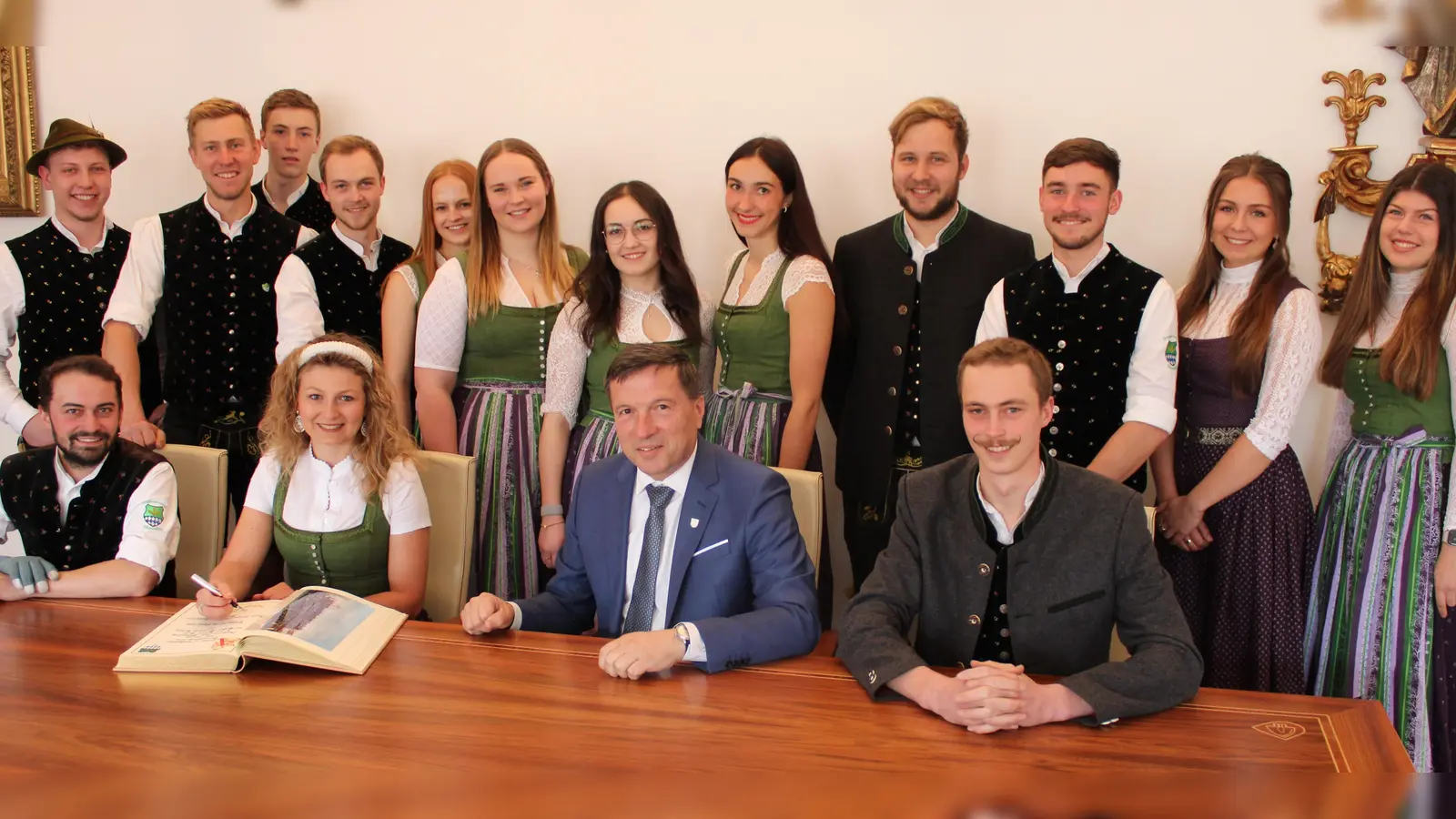 Der Vorsitzende der Jungbauernschaft Altenerding, Josef Fehlberger (sitzend, rechts), sowie das „Brautpaar“ Georg Bichlmaier und Sophia Wurzer (sitzend, von links) haben sich im Amtszimmer von Oberbürgermeister Max Gotz ins Goldene Buch der Stadt Erding eingetragen. (Foto: Stadt Erding)