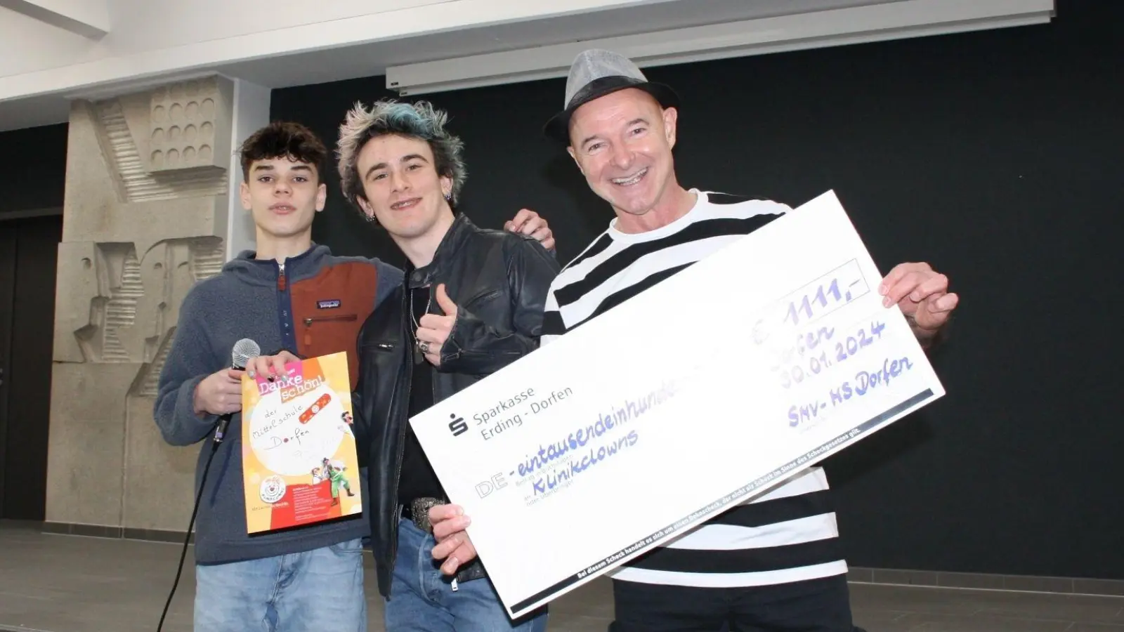 Die Schülersprecher der Mittelschule Dorfen, Noel Seisenberger (li.) und Lenny Nagler, überreichten KlinikClown „Lupino Valentino“ den Spendenscheck. (Foto: Florian Emberger)