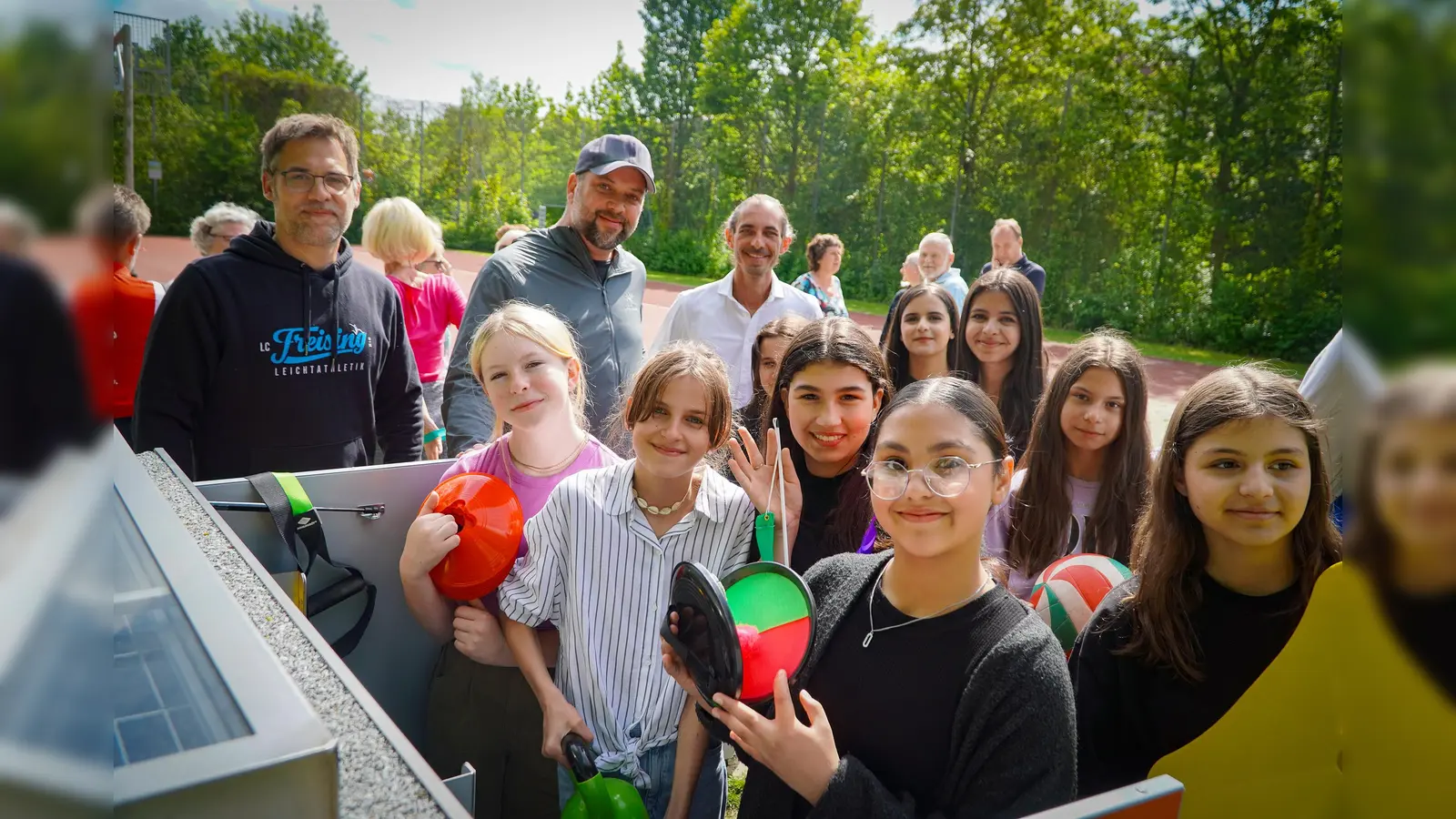 Große Freude bei der Eröffnung der SportBox (von links): Andreas Pirkelmann, Vorsitzender LC Freising, Oberbürgermeister Tobias Eschenbacher sowie Sportreferent Jürgen Mieskes mit den Schülerinnen der Mittelschule Lerchenfeld beim Testen des Equipments. (Foto: Stadt Freising)